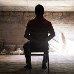 Israeli Cabinet’s Shocking Hostage Release Decision Person tied to chair in dimly lit room.