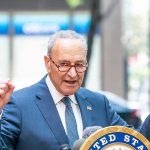 Schumer DEMANDS Uprising—Washington on Edge Man in suit and glasses speaks passionately at podium.