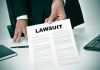 Person holding a document titled LAWSUIT in office.