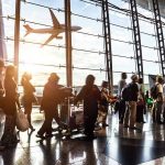 Airport Massacre Averted — Family Heroics! Crowd of travelers in airport terminal with airplane outside.