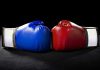 Blue and red boxing gloves facing each other.