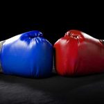 Blue and red boxing gloves facing each other.