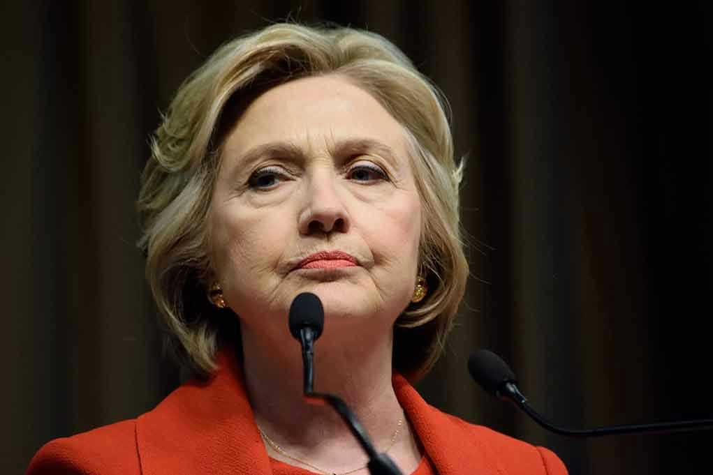 Woman in red jacket speaks into two microphones.