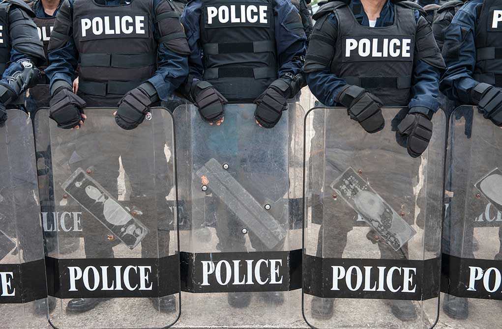Police officers in riot gear holding shields.