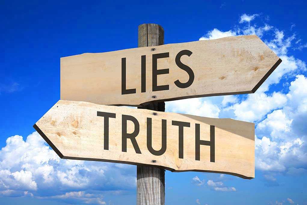 Signs pointing to Lies and Truth against sky.