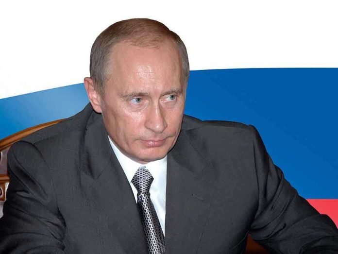 shutterstock_129093563.jpg A serious-looking man in a suit sitting at a table with a Russian flag in the background