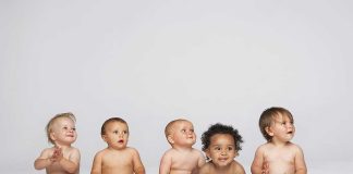 Five diverse babies sitting on a neutral background, displaying playful expressions