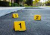 Two Sisters ARRESTED — Three Students DEAD! Crime scene markers on asphalt with bullet casing.