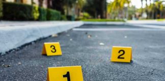 Crime scene markers on asphalt with bullet casing.