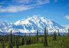 Trump Hits Leftist Ban – Millions of Acres Unlocked Snow-covered mountain under blue sky with green foreground.