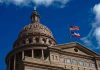 Massive Texas Gang Raid Shocks Border Town Building dome with US and Texas flags, blue sky.