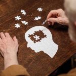 Royals’ Fate: Psychic’s Stunning Health Crisis Prediction Elderly person completing head-shaped jigsaw puzzle.