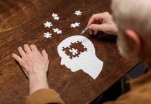 Elderly person completing head-shaped jigsaw puzzle.