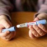 PESKY Legal Challenges Rock Drug Price Deal Hands holding an Ozempic injection pen.