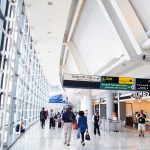 FAA SLASHES Flights — New MANDATE Shakes Travelers People walking in a brightly lit airport terminal.