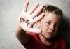 A child holding up a hand with the word stop written on it