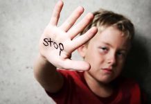 A child holding up a hand with the word stop written on it