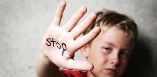 A child holding up a hand with the word stop written on it