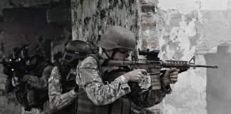 Soldiers in tactical gear advancing through a damaged building