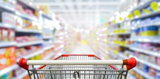 Shopping cart in aisle of grocery store.