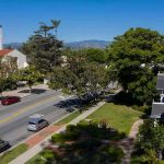 Street with church, parked cars, and trees.