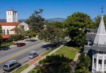 Street with church, parked cars, and trees.