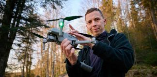 Person holding a drone in a forest.