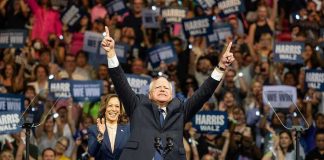People cheering at a political rally, man raising arms.