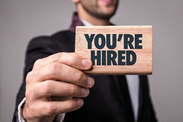 Person holding a Youre Hired sign.