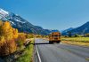 Terrifying School Collapse Caught On Camera A yellow school bus driving on a rural road surrounded by autumn trees and mountains