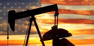Silhouette of an oil pump jack against a sunset background with an American flag overlay