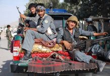 18,000 Afghan Evacuees Were on Terror Watchlist Three armed soldiers sitting on the back of a military vehicle in an urban setting