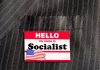 Socialist Mayor Rolls the Dice Hello my name is Socialist name tag on suit.
