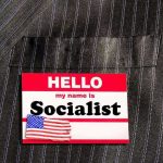 Socialist Mayor Rolls the Dice Hello my name is Socialist name tag on suit.