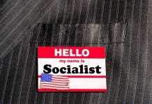 Socialist Mayor Rolls the Dice Hello my name is Socialist name tag on suit.