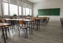 School Moral Crisis Rocks America Empty classroom with desks, chairs, windows, and chalkboard.
