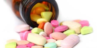 A variety of colorful pills and tablets spilled from a brown medicine bottle