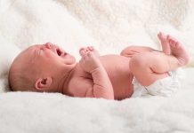 Child Was Tortured To Death A newborn baby lying on a soft blanket, crying with a distressed expression