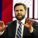 Vance Shocks World With UNPRECEDENTED Armenia Mission Man in suit gesturing with hands on stage.