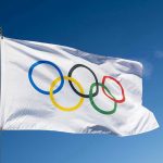 Wasserman’s Olympic Role Under FIRE After Leaks Olympic flag waving against clear blue sky.