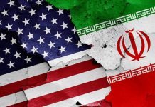 Bunker-Buster Blitz Hits Iran Coast Cracked American and Iranian flags on a wall.