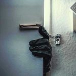 Gloved hand opening door with security chain.