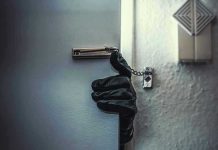 Gloved hand opening door with security chain.