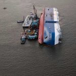 Shock Attack: Odesa in Flames! Capsized ship with cranes and tugboats around it.