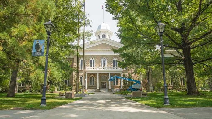 Historic stone building surrounded by trees and lampposts.