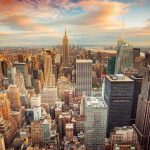 Manhattan Rent Hits Unbelievable $5,000 Mark! New York City skyline at sunset with tall buildings.
