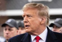 Trump’s ‘Bad Timing’ Drama – Iran vs. Family Man in suit and red tie speaking outside.