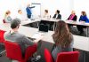 Hochul’s $500 Million Pension Gamble A diverse group of professionals engaged in a meeting with a presenter at a whiteboard
