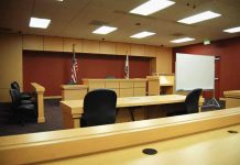 Hunter Plea Deal COLLAPSES – PANIC Ensues! Interior view of an empty courtroom with wooden furniture and American flags