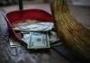 Stanford: $50,000 to Drag Troupe, $10,000 to Veterans Association Broom sweeping dollar bills into red dustpan floor